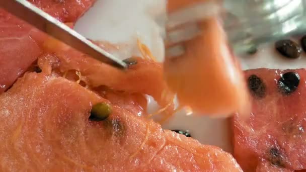 Een dame is het eten van watermeloen met een mes en vork — Stockvideo