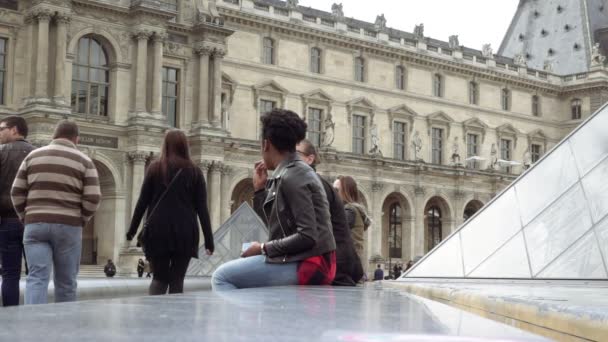 Мультирасовые туристы сидят на каменном парапете — стоковое видео