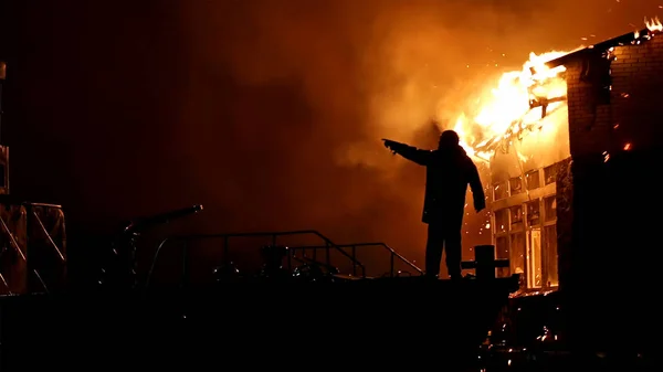 Hus i brand. Storbrand. Brandman bekämpar brand. — Stockfoto