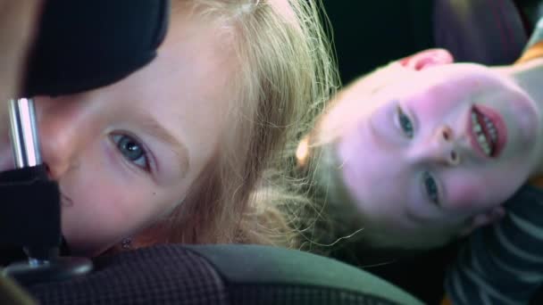 Sonriendo y riendo a los niños en un asiento de coche — Vídeos de Stock