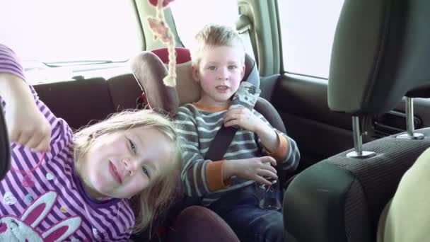 Χαμογελαστός και γελά, τα παιδιά σε μια καθίσματα αυτοκινήτου — Αρχείο Βίντεο