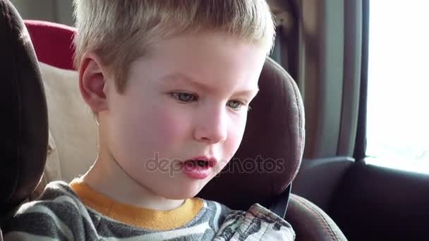 Söt pojke i en bilbarnstol för barn ler och skrattar — Stockvideo