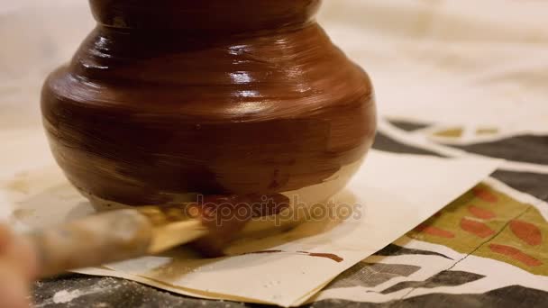 Ceramista está pintando olla de arcilla o jarrón — Vídeo de stock