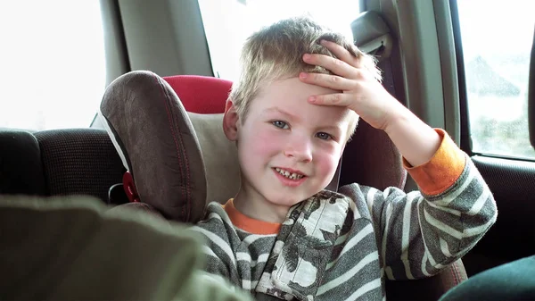 Mignon garçon dans un enfant voiture siège sourit et rit — Photo