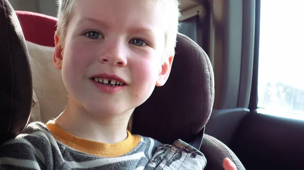 Mignon garçon dans un enfant voiture siège sourit et rit — Photo