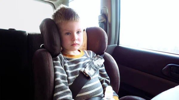 Rapaz bonito em um assento de carro de criança — Fotografia de Stock