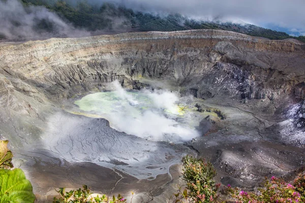 Poas Volcano Crater in Costa Rica, Central America. The crater of a volcano spews smoke.