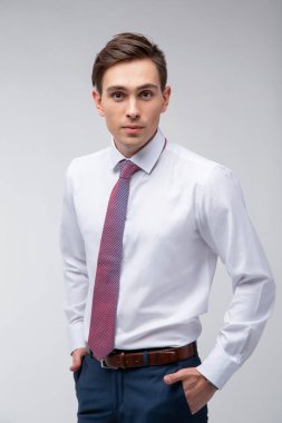 Siyah kısa saçlı, beyaz gömlekli, beyaz gömlekli, atölyesinde beyaz bir kravatı olan genç, yakışıklı bir adam.