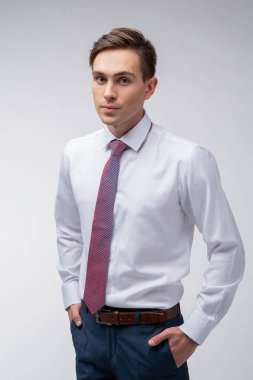 Siyah kısa saçlı, beyaz gömlekli, beyaz gömlekli, atölyesinde beyaz bir kravatı olan genç, yakışıklı bir adam.