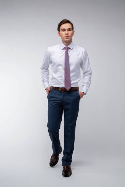 Siyah kısa saçlı, beyaz gömlekli, beyaz gömlekli, atölyesinde beyaz bir kravatı olan genç, yakışıklı bir adam.