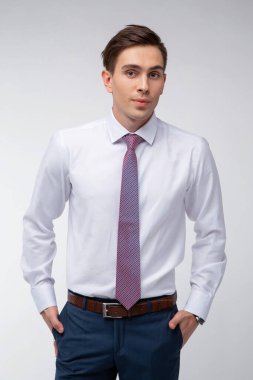 Siyah kısa saçlı, beyaz gömlekli, beyaz gömlekli, atölyesinde beyaz bir kravatı olan genç, yakışıklı bir adam.