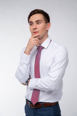 Siyah kısa saçlı, beyaz gömlekli, beyaz gömlekli, atölyesinde beyaz bir kravatı olan genç, yakışıklı bir adam.