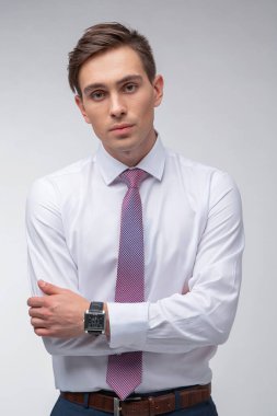 Siyah kısa saçlı, beyaz gömlekli, beyaz gömlekli, atölyesinde beyaz bir kravatı olan genç, yakışıklı bir adam.