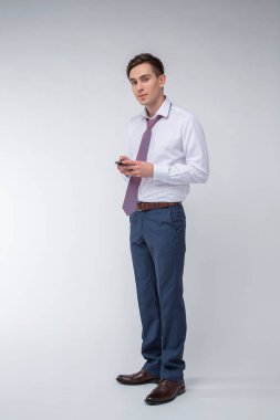 Siyah kısa saçlı, beyaz gömlekli, beyaz gömlekli, atölyesinde beyaz bir kravatı olan genç, yakışıklı bir adam.