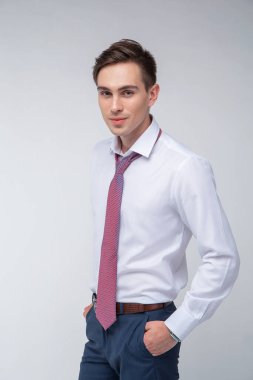 Siyah kısa saçlı, beyaz gömlekli, beyaz gömlekli, atölyesinde beyaz bir kravatı olan genç, yakışıklı bir adam.