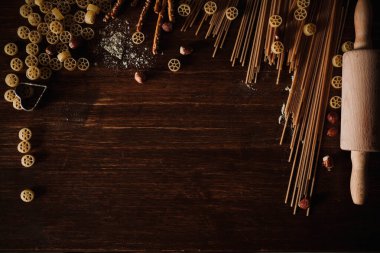 Üst sıra makarna ve ahşap masa manzarasında taze malzemeler.