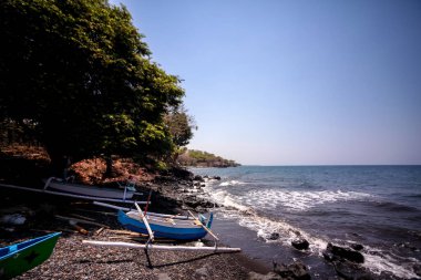 Bali 'nin kuzeyinde, Endonezya' da tekneleri ve volkanik siyah kumları olan bir sahil panoraması.