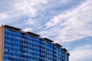 Ofis binasının modern cephesi, çelik bir yapıda parlak pencereleri olan soyut bir parçadır. Kartvizit, el ilanı, yazı veya logo için yeri olan afiş için harika bir arkaplan