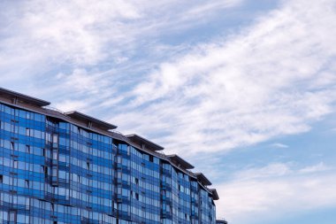 Ofis binasının modern cephesi, çelik bir yapıda parlak pencereleri olan soyut bir parçadır. Kartvizit, el ilanı, yazı veya logo için yeri olan afiş için harika bir arkaplan