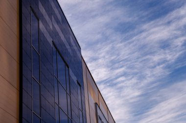 Ofis binasının modern cephesi, çelik bir yapıda parlak pencereleri olan soyut bir parçadır. Kartvizit, el ilanı, yazı veya logo için yeri olan afiş için harika bir arkaplan