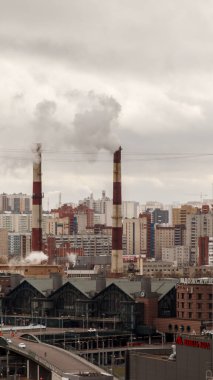 Çevre ve hava kirliliği, ekolojik sorunlar kavramı. Fabrika bacalarından gri bulutlu gökyüzüne doğru duman çıkıyor. Şehir manzarası.