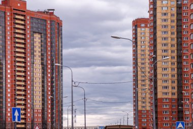 Çok katlı bina. Evleri, çok katlı binaları ve mimarisi olan modern şehir manzarası, yol lambaları ve binaların arkasındaki mavi gökyüzü.