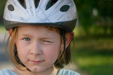 Koruyucu kasklı mutlu kız parkta scooter ve kaykay sürüyor..
