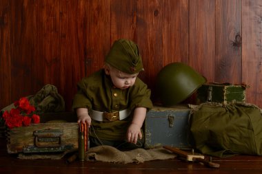 Zafer Günü, 9 Mayıs 1941-1945, üniformalı küçük bir çocuk eski kutuların üzerinde oturuyordu, eski askeri atmosfer.