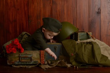 Zafer Günü, 9 Mayıs 1941-1945, üniformalı küçük bir çocuk eski kutuların üzerinde oturuyordu, eski askeri atmosfer.