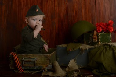 Zafer Günü, 9 Mayıs 1941-1945, üniformalı küçük bir çocuk eski kutuların üzerinde oturuyordu, eski askeri atmosfer.