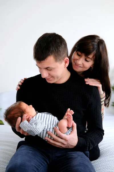 Fotoğrafta, dört kişilik sevgi dolu bir aile yatakta oturuyor. Annemin kucağında yeni doğmuş bir bebek var. aile aşkı.