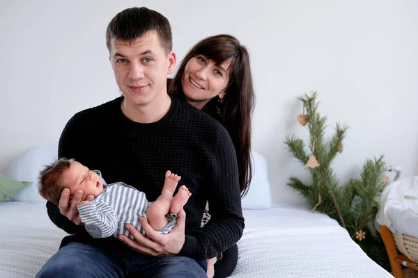 Fotoğrafta, dört kişilik sevgi dolu bir aile yatakta oturuyor. Annemin kucağında yeni doğmuş bir bebek var. aile aşkı.