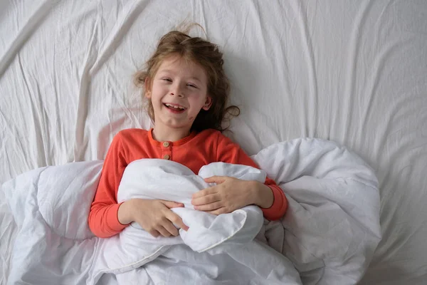 잠옷을 소녀가 아래하얀 침대에 — 스톡 사진