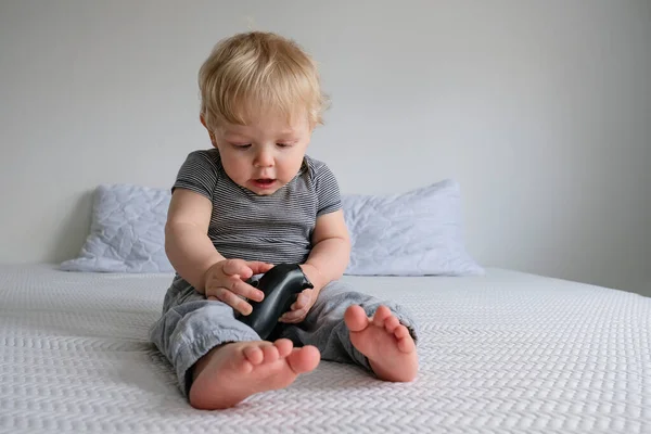 Niño Con Ropa Lana Sienta Una Cama Blanca Juega Videojuegos — Foto de Stock