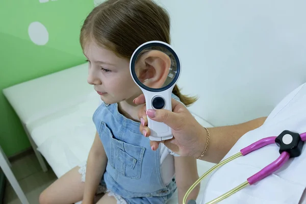 Tıp, sağlık ve pediatri konsepti - klinikte veya hastanede kız hastaların kulaklarını kontrol eden kadın çocuk doktoru