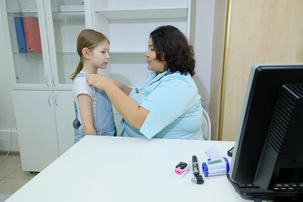 The girl came to the pediatrician for an examination. the doctor conducts an external examination and diagnosis of the patient at a reception in the office