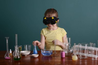 Güvenlik gözlüklü kız evde kimyasallarla deney yapıyor. Evde okul deneyleri.