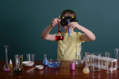 Güvenlik gözlüklü kız evde kimyasallarla deney yapıyor. Evde okul deneyleri.