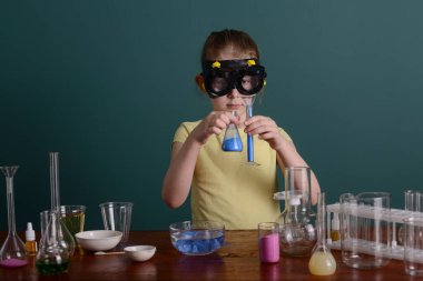 Güvenlik gözlüklü kız evde kimyasallarla deney yapıyor. Evde okul deneyleri.