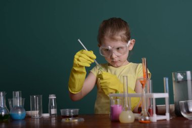 Güvenlik gözlüklü kız evde kimyasallarla deney yapıyor. Evde okul deneyleri.