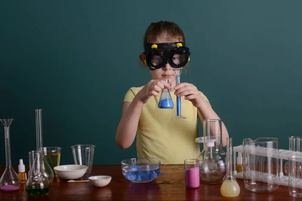 girl in safety glasses at home doing experiments with chemicals. school experiments at home.