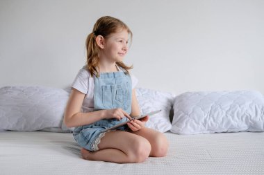 Kız evde, yatağın üzerinde oturuyor ve elinde bir dizüstü bilgisayar var. Liseli bir kız öğreniyor ve dizüstü bilgisayarda oyunlar oynuyor. Karantina kendi kendini eğitme