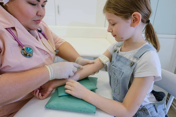 Bir hemşire bir kızı aşılıyor, virüs enfeksiyonuna karşı bir aşı COVID - 19. Doktor çocuğa iğne yapıyor.