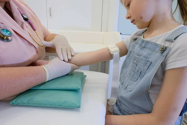 Bir hemşire bir kızı aşılıyor, virüs enfeksiyonuna karşı bir aşı COVID - 19. Doktor çocuğa iğne yapıyor.
