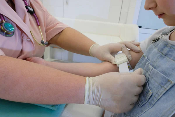 Bir hemşire bir kızı aşılıyor, virüs enfeksiyonuna karşı bir aşı COVID - 19. Doktor çocuğa iğne yapıyor.