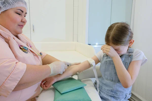 Bir hemşire bir kızı aşılıyor, virüs enfeksiyonuna karşı bir aşı COVID - 19. Doktor çocuğa iğne yapıyor.