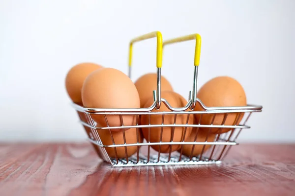 supermarket grocery basket with chicken eggs stands on a wooden table