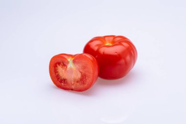 Kırmızı domatesler beyaz arka planda ikiye bölünmüş.