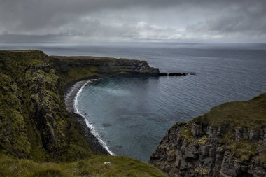  Kuzey İzlanda 'daki Grimsey Adası' nın dışında Kuzey Kutup Dairesi 'nin ötesinde manzara. Okyanus açık bir buz mavisi, gökyüzü biraz bulutlu ve kayalıkların altında bir sürü kaya var.