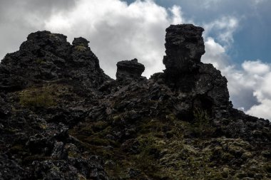 Mvatn Gölü bölgesinde yer alan volkanik oluşum Dimmuborgir 'in görüntüsü. Soğutulmuş lav oluşumları biraz bitki örtüsüyle siyahtır, gökyüzü bulutludur.